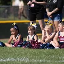Young Titans cheerleaders sitting on the grass with pom-poms