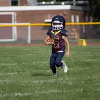 Young Titans football player carrying the ball on the field
