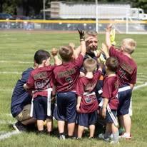 Coach celebrating with young flag football players