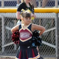 Young Titans cheerleader with pom-poms by the fence