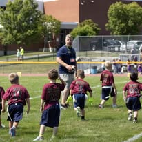 Coach leading young flag football players on the field