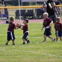 Young flag football players reaching for the ball together