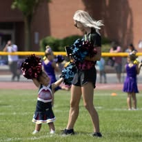Tiny Titans cheerleader dancing with an older squad member