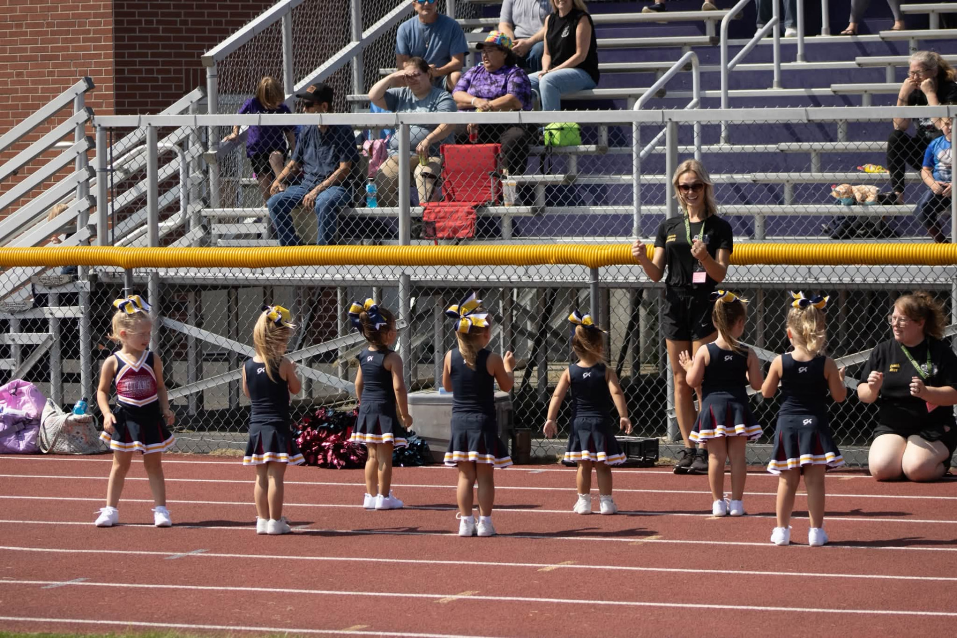Young Titans cheerleaders with coaches on the track